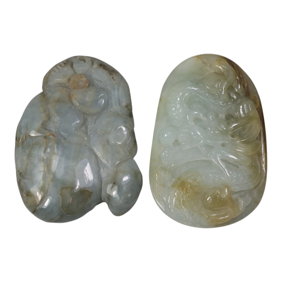 Lot of 2 Antique Oriental Chinese Jadeite Jade Carved Pendants, 44AG: Carved from pale green jadeite jade with natural yellowish-brown inclusions and marbling, the two pendants feature distinct relief motifs. The left pendant depicts stylized forms, likely representing 
