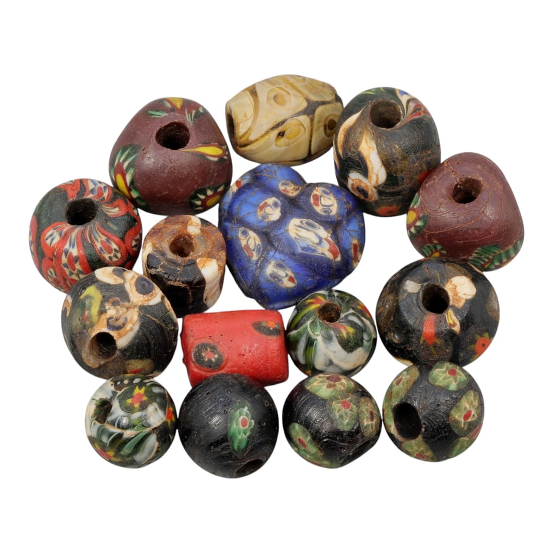 A Lot of 15 Antique/ Vintage Artisan Glass Trade Beads, 28WM: A curated collection of 15 glass trade beads, varying in form from spherical, barrel, and heart-shaped to polygonal, all with central perforations. The beads feature intricate mosaic, trailed, and app