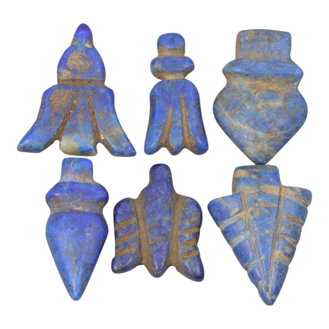 Lot of 6 Islamic Lapis Lazuli Amulet Beads, Circa Medieval Islamic Period, 60WM: A group of six hand-carved amulet beads crafted from lapis lazuli, showcasing the stone's characteristic deep blue hue with natural calcite and pyrite inclusions, alongside surface patination and eart