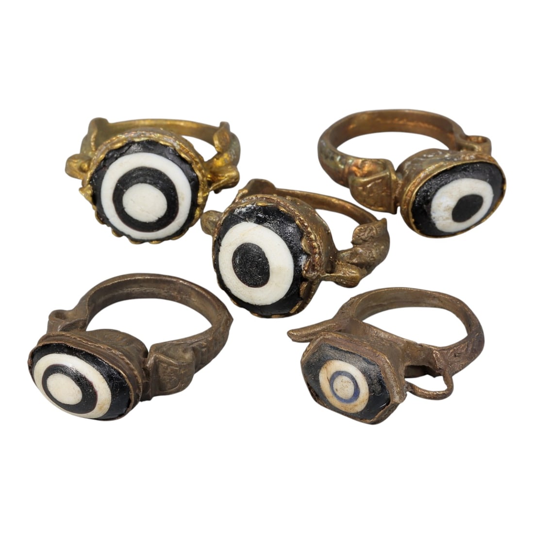 Lot of 5 Antique Qajar Period Gilt & Metal Evil Eye Glass Rings, 8AD: A collection of five antique rings from the Qajar period (19th century), each set with traditional "evil eye" glass cabochons. Most rings feature classic black-and-white concentric bullseye patterns, 