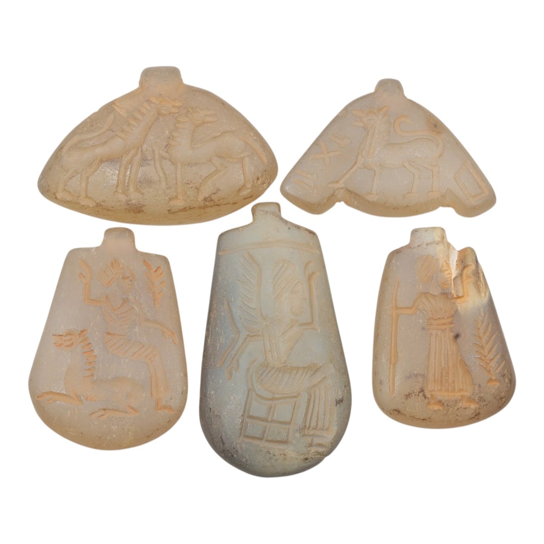 Lot of 5 Ancient Sasanian Chalcedony Amulet Pendants, Circa 3rd-7th Century CE, 58WT: Carved from chalcedony in natural hues, the group consists of five amulet pendants of varying forms. The pieces likely include zoomorphic, geometric, or symbolic motifs typical of Sasanian-period deco