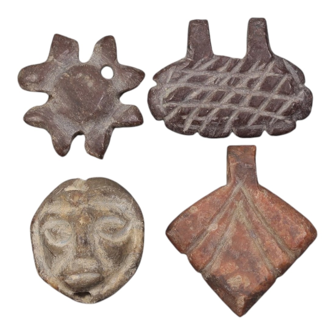Lot of 4 Ancient Coptic Egyptian Red Stone Amulets, Circa Roman to Coptic Era, 16AE: The group comprises four small carved stone amulets in varying reddish-brown and brown tones. One example is star-shaped with a central disc and a perforation for suspension. A second is a basket-like