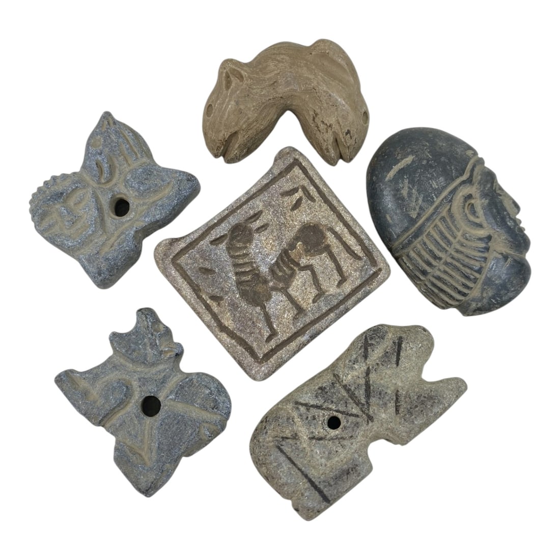 A Lot of 6 Ancient Near Eastern Stone Amulets and Seals, 18AC: The group comprises six carved stone objects, exhibiting varied earthy tones and surface patina consistent with antiquity. The collection features a diverse range of forms, including a square seal wit