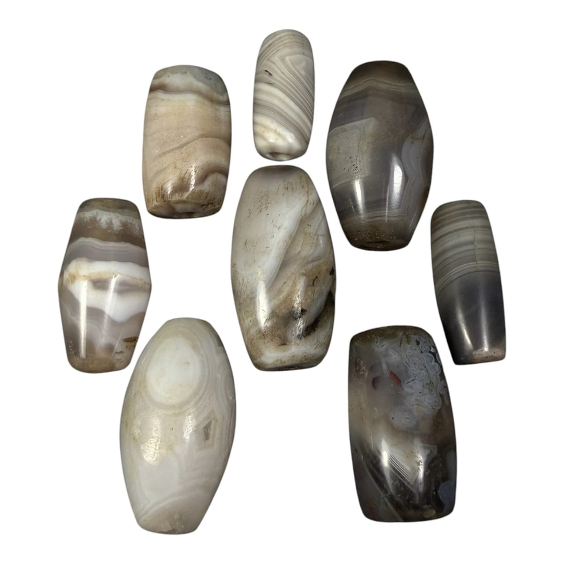 Lot of 8 Himalayan Banded Agate Beads, Ancient to Antique Period, 14AH: A group of eight beads crafted from banded agate, exhibiting natural tonal variations ranging from creamy white and light grey to muted brownish hues, with characteristic concentric, wavy, and linear 
