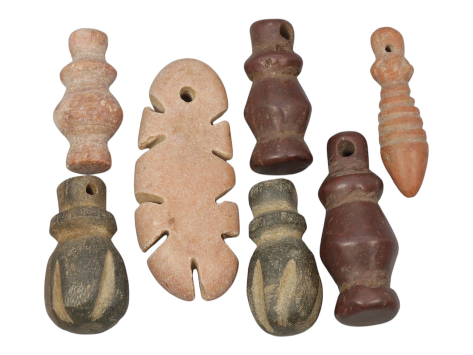 Lot of 7 Ancient Coptic Egyptian Multi-Stone Amulets, Circa Roman to Coptic Era, 65WT: Carved from various earth-toned stones in shades of pinkish-beige, dark grey, and reddish-brown, the group consists of seven distinct amulets, ranging in size from 2 cm to 3.5 cm (0.79-1.38 in.). The 