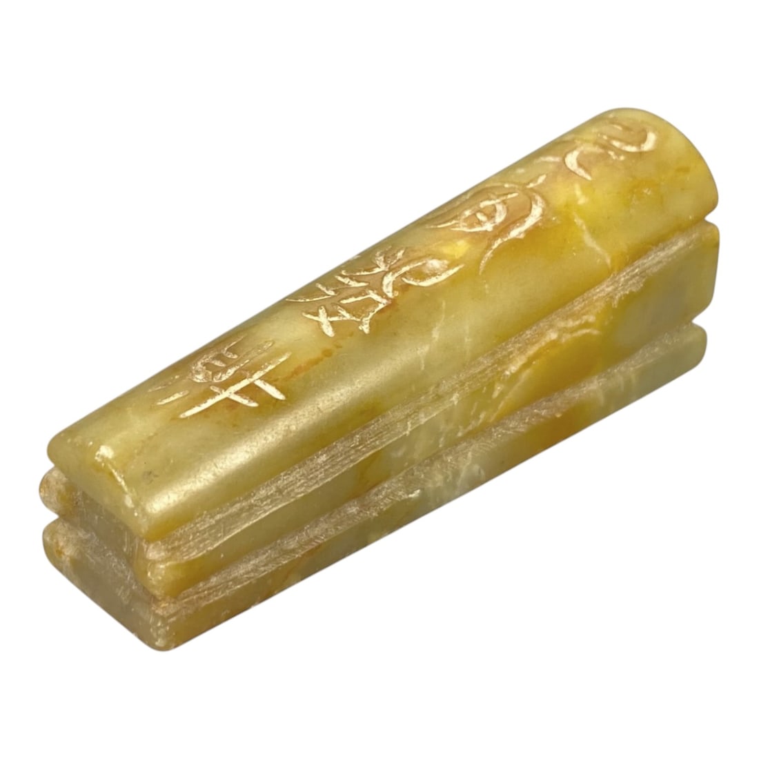 A Chinese Hetian Jade Coffin-Form Amulet, 20th Century, 86ZH: Carved from Hetian jade, this amulet is formed in the shape of a miniature coffin, with a rectangular body and a slightly curved, raised lid. The material exhibits a pale yellowish-green to honey-yell