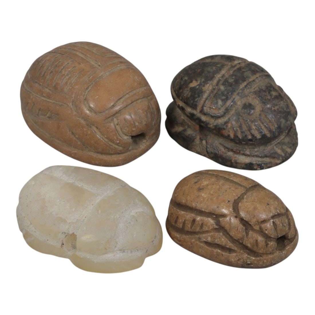 Lot of 4 Ancient Coptic Egyptian Multi-Stone Scarab Amulets, Circa Roman to Coptic Era, 85AH: Carved from diverse materials including terracotta-toned stone, dark speckled stone, translucent calcite/quartz, and light brown stone, the group consists of four distinct scarab amulets, ranging in s