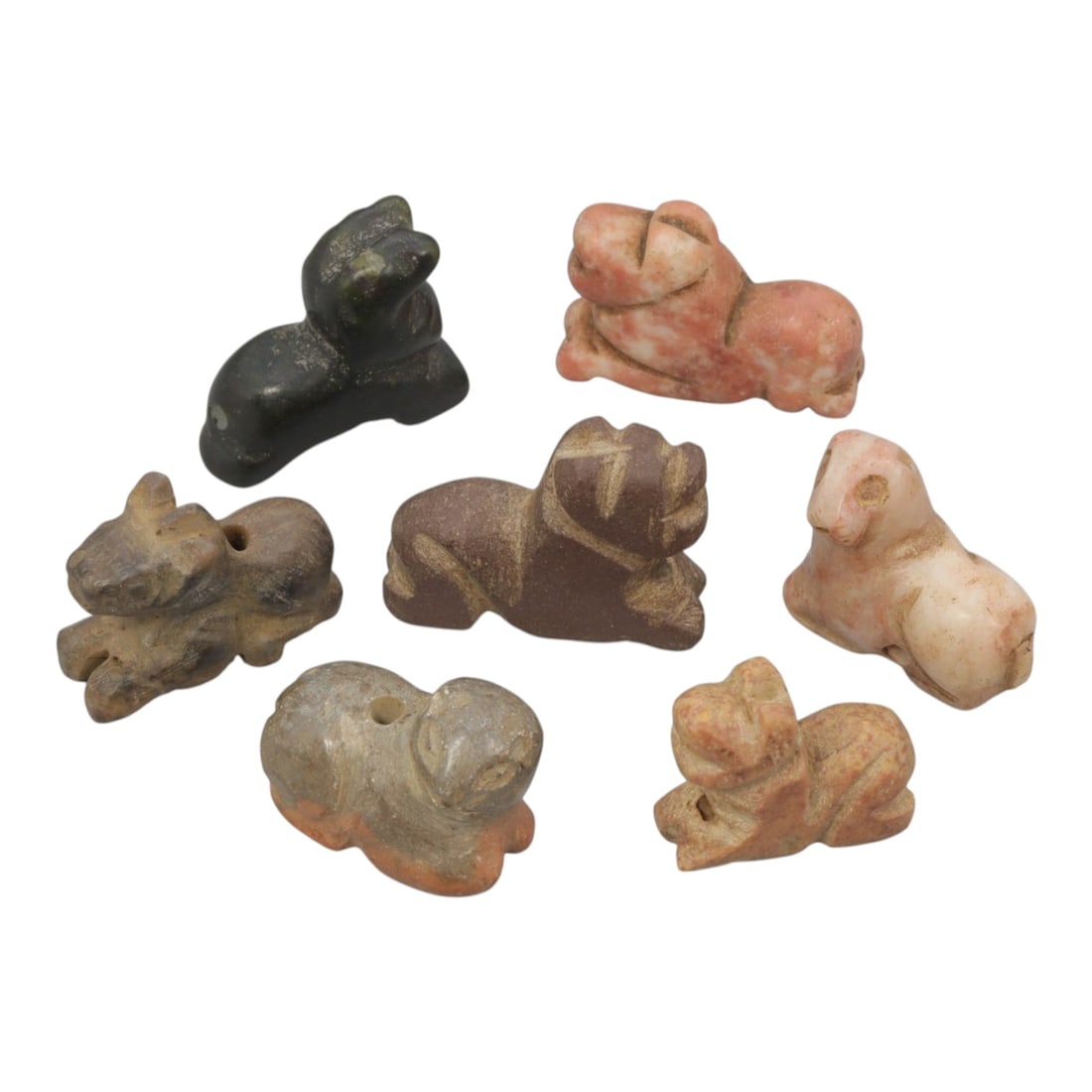 Lot of 7 Ancient Bactrian Multi-Stone Zoomorphic Amulets, 80AH: Carved from various earth-toned stones including dark green, pinkish marble, brown, and grey varieties, the group consists of seven distinct zoomorphic amulets, ranging in size from 2 cm to 2.5 cm (0.