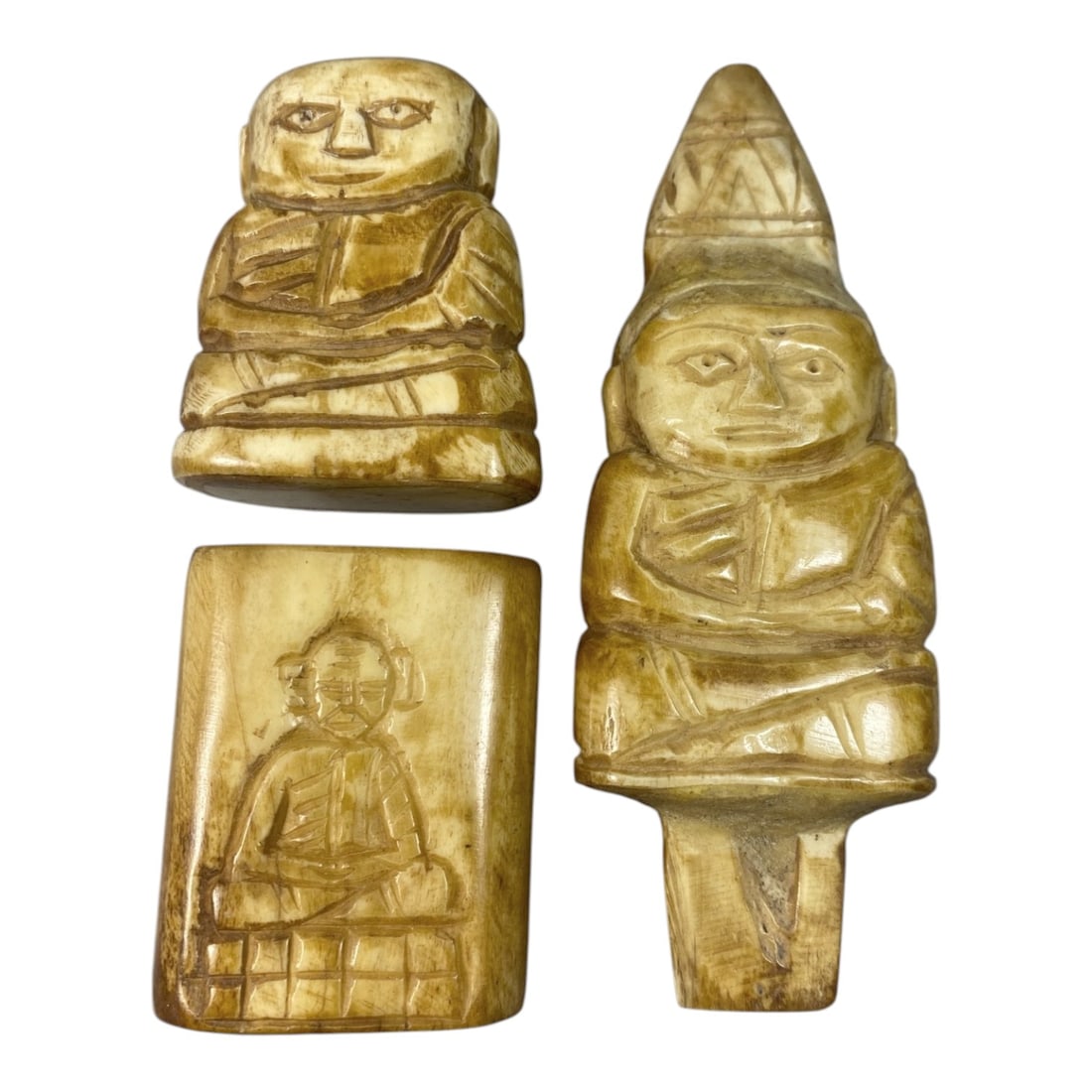 Lot of 3 Southeast Asian Bone Buddhist Amulets, 93AC: The lot comprises three carved bone Buddhist amulets, each depicting a seated figure. Two examples are fully three-dimensional carvings, while the third is a plaque with an incised figure. The seated 