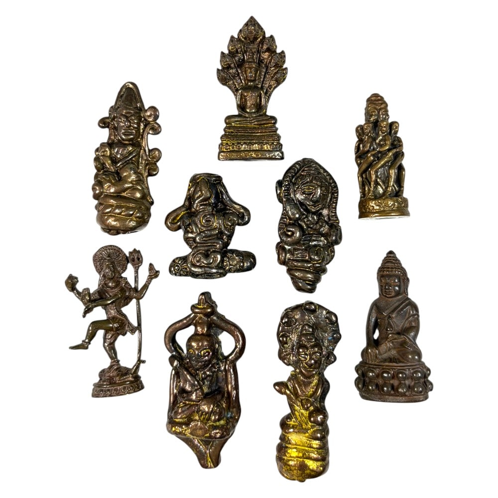 A Lot of 9 Vintage Southeast Asian Metal Amulet Figurines, 51AA: Comprising nine small cast metal pieces ranging from 2.5 to 4.5 cm in height. The collection features a diverse array of devotional imagery, including Naga-protected Buddha, dancing Shiva, Ganesha, an