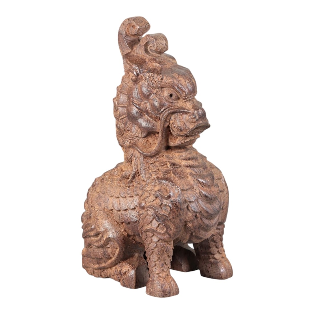 A Chinese Agarwood Qilin Figurine, 20th Century, 69FC: Carved from agarwood with natural tonal variation and a warm, deep brown patina, the figurine depicts a seated qilin (mythical auspicious beast). The creature is rendered in the round, with a detailed