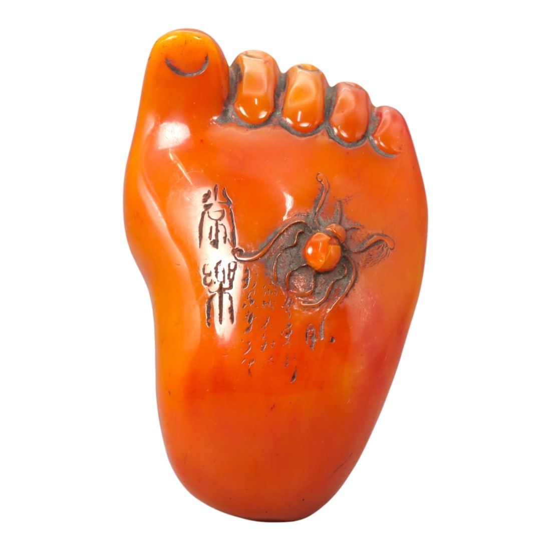 A Chinese Amber-Resin Foot-Form Carving, 20th Century, 64FC: Modeled from translucent orange-toned amber resin, the object is carved in the form of a stylized human foot, rendered in the round with simplified anatomical features. The toes are indicated in shall