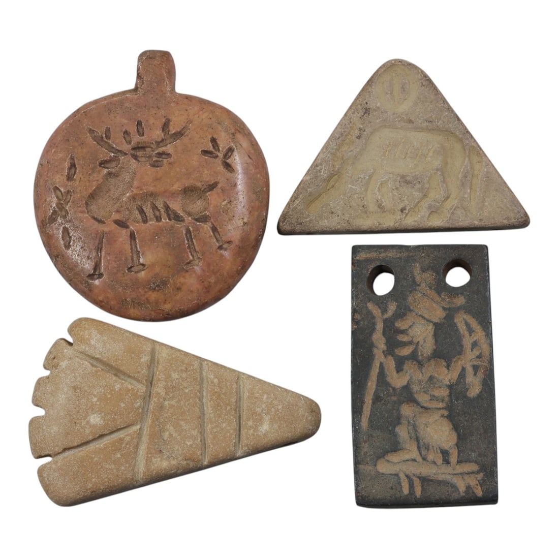 Lot of 4 Ancient Near Eastern Stone Amulets, 4th-3rd Millennium BCE, 34AE: The group comprises four stone amulets of varied forms and iconography, likely associated with Near Eastern Bronze Age ritual contexts. The first is a circular pendant with a suspension loop, carved f