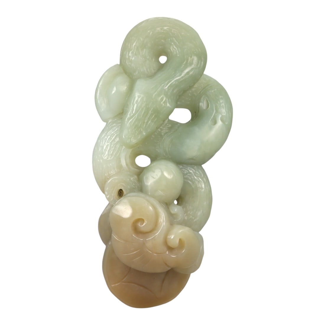A Chinese Jade Intertwined Serpents and Lingzhi Pendant, 20th Century, 36YA: Carved from pale celadon jade with areas of creamy white and warm honey-colored tonal variation, the pendant is worked as a vertically oriented composition carved in the round with openwork elements. 