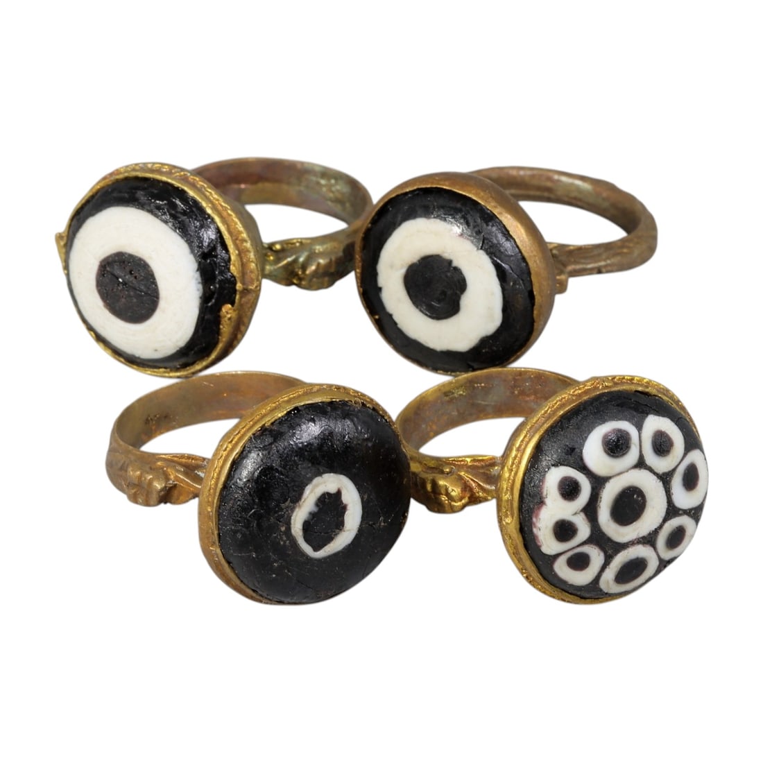 Lot of 4 Antique Qajar Period Gilt Evil Eye Glass Rings, 14AD: This collection includes four gilt-metal rings from the Qajar period (19th century), each adorned with traditional "evil eye" glass cabochons. Three rings feature classic black-and-white concentric bu