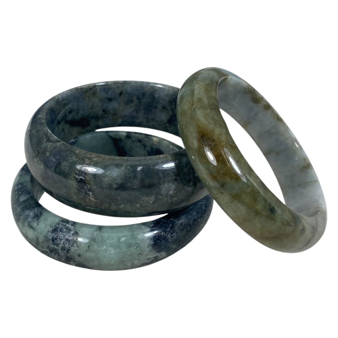 Lot of 3 Chinese Polished Jadeite Jade Bracelets (Bangles), 84AC: Each bracelet is a smooth, uncarved circular bangle crafted from jadeite. The pieces exhibit varied natural coloration and inclusions, including deep grey-green with mottled black veining, lighter gre
