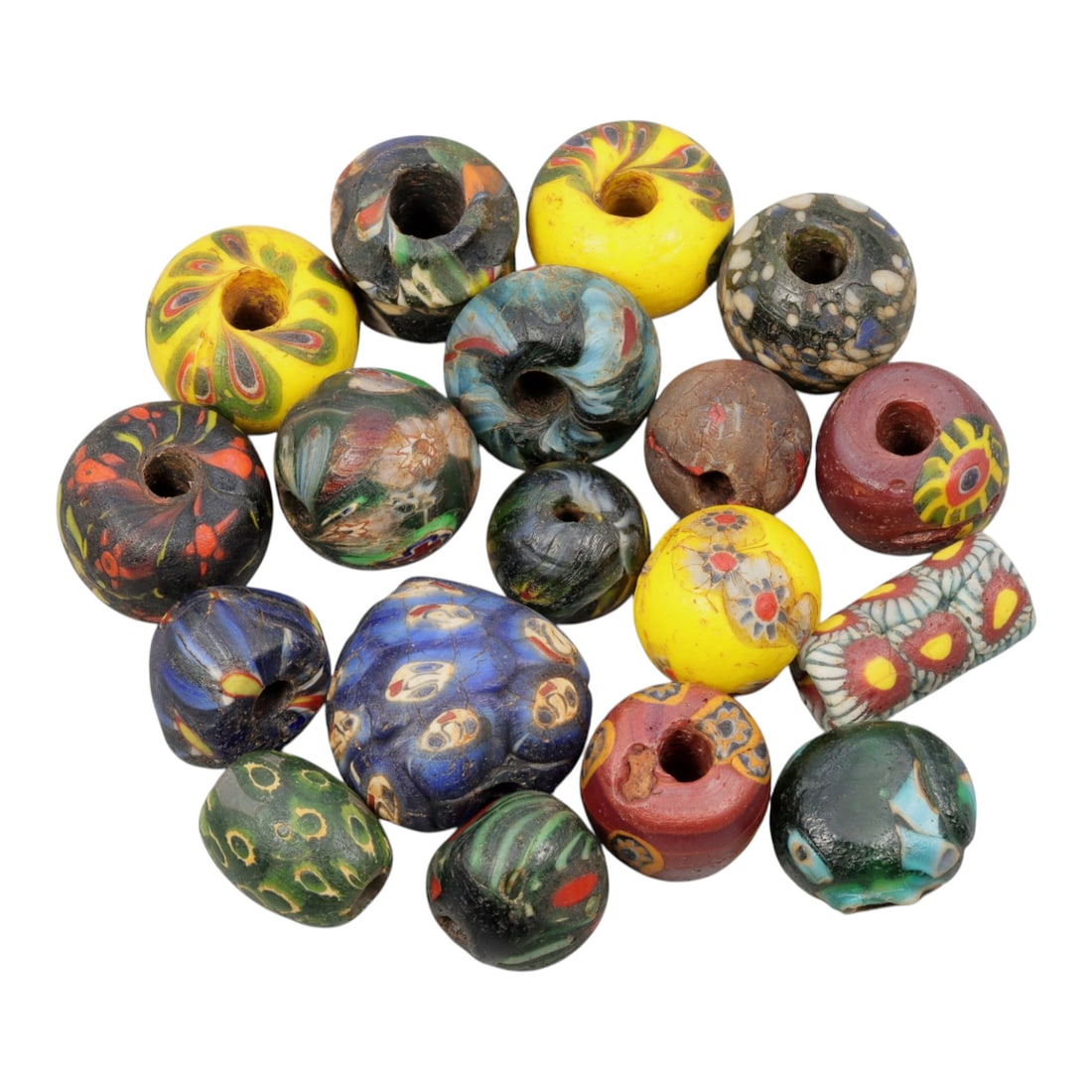 A Lot of 17 Antique/ Vintage Artisan Glass Trade Beads, 26WM: A curated collection of 17 glass trade beads, varying in form from spherical, barrel, and cylindrical to polygonal, all with central perforations. The beads feature intricate mosaic, trailed, and appl