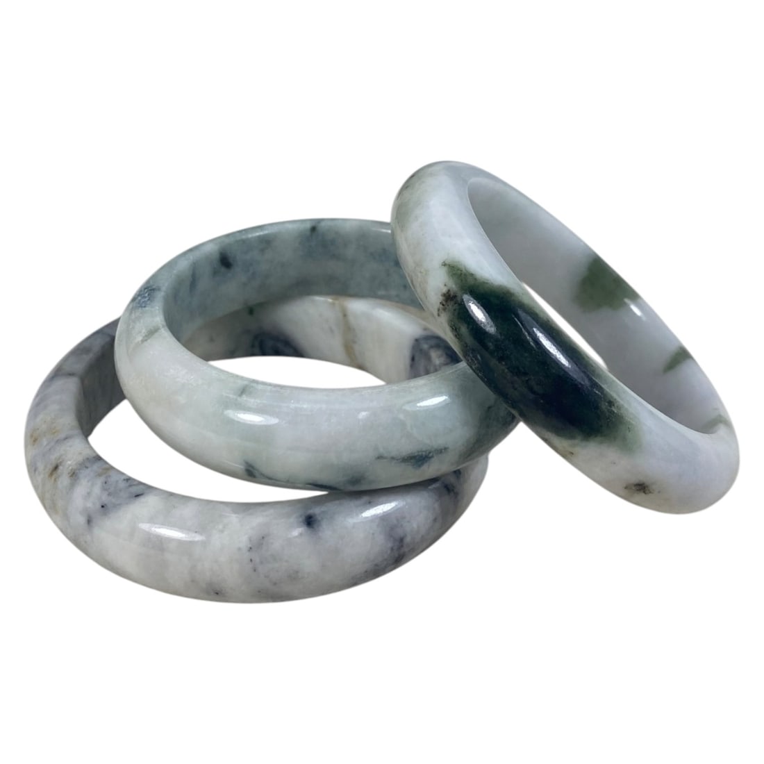 Lot of 3 Chinese Polished Jadeite Jade Bracelets (Bangles), 89AC: Each bracelet is a smooth, uncarved circular bangle crafted from jadeite. The pieces exhibit varied natural coloration, including pale white with deep green and grey inclusions, light grey-green with 