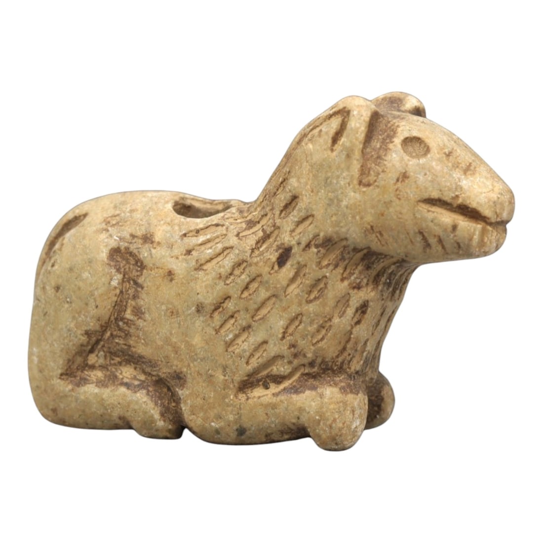 Ancient Stone Canine Figurine - Near Eastern Ritual Relics, 95ZP: Carved from warm tan stone, this reclining canine figurine features a stylized head with incised eyes, pointed ears, and a gently curved mouth. The neck and upper body display textured, linear incisio