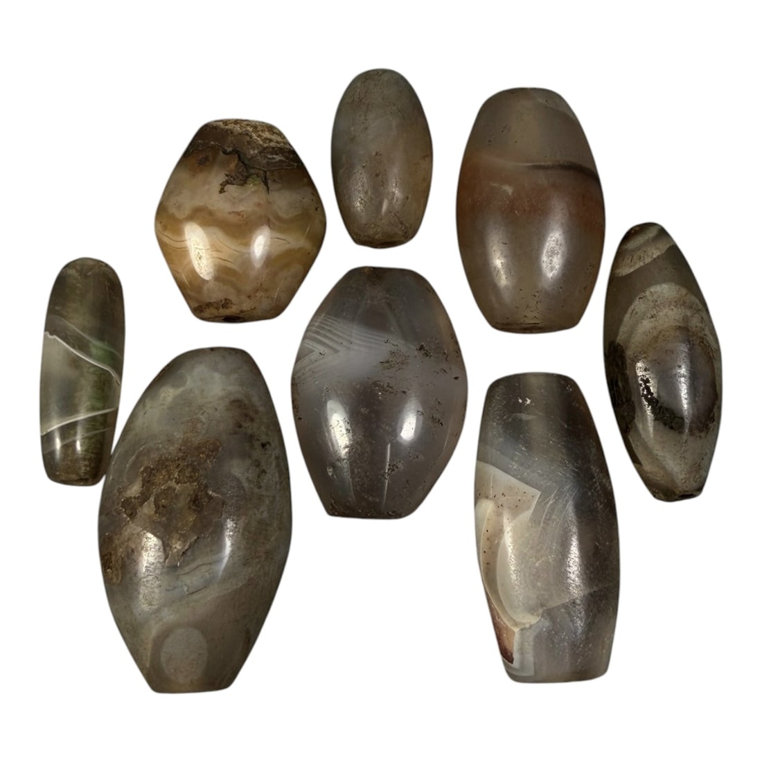 Lot of 8 Himalayan Banded Agate Beads, Ancient to Antique Period, 92AG: A group of eight beads crafted from banded agate, exhibiting natural tonal variations including translucent grey, brown, and subtle cream hues, with characteristic wavy, linear, and occasional eye-lik