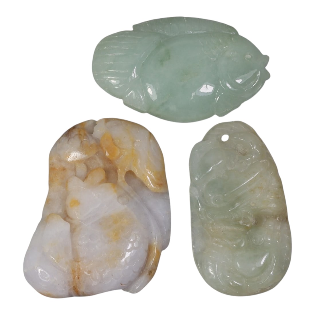 Lot of 3 Antique Oriental Chinese Jadeite Jade Fish Pendants, 41AG: Carved from jadeite jade with varied natural tones including pale green, light green with lavender, and yellowish-brown inclusions, the three pendants each depict fish motifs. The top pendant is a sim
