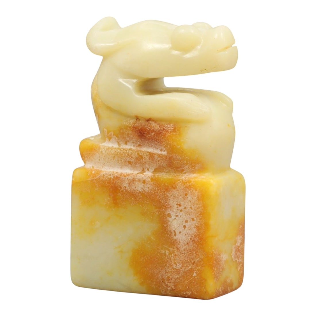 A Chinese Jade Dragon Seal, Ancient Style, 20th Century, 43YC: The seal is carved from jade of pale cream tone with areas of russet and ochre coloration, the stone displaying natural mottling and translucency. It is worked as a square-section seal with a stepped 