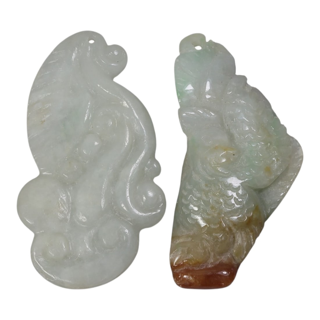 Lot of 2 Antique Oriental Chinese Jadeite Jade Pendants, 49AG: The lot comprises two free-form jadeite pendants. The left pendant is carved from pale milky-white jadeite with faint green inclusions, featuring stylized ruyi scroll motifs and integrated suspension 
