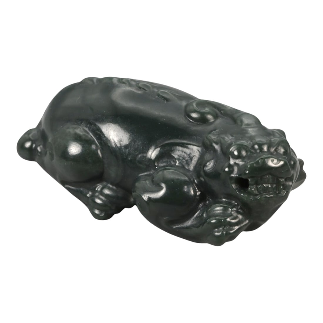 A Chinese Nephrite Jade Pixiu Figure, 20th Century, 94FB: Carved from dark green nephrite jade with areas of translucency and a high, even polish, the figure is modeled as a recumbent pixiu, shown with the head turned slightly to one side. The creature is re