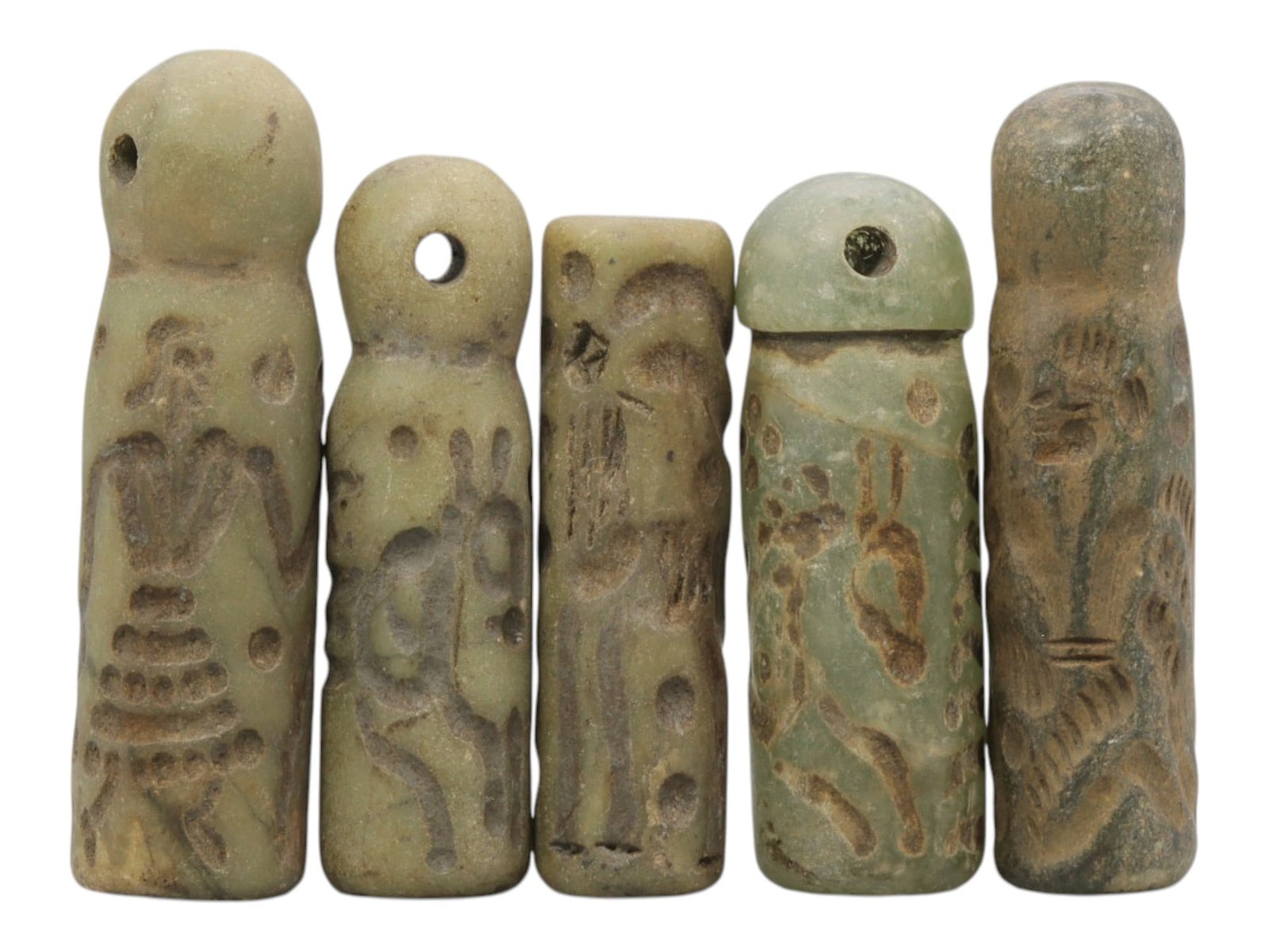 A Lot of 5 Ancient Mesopotamian Serpentine Cylinder Seals, 42WP: A curated lot of five ancient Mesopotamian-style cylinder seals, carved from serpentine stone with natural patination and wear consistent with age. Each seal features a domed top with a suspension hol