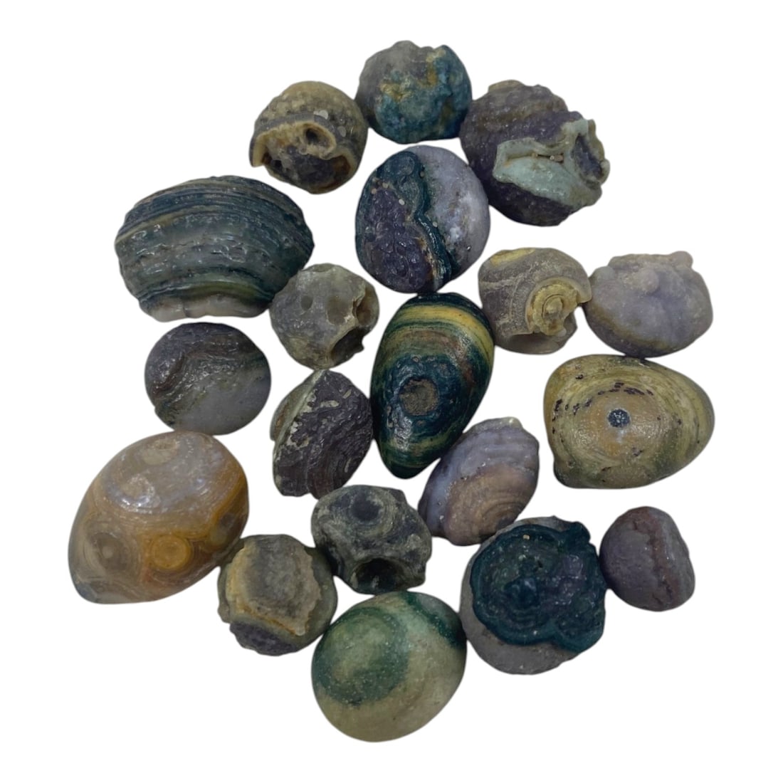 Lot of 19 Sino-Mongolian Agate Eye Beads, 97AC: Each bead is formed from naturally weathered agate, displaying varied earthy tones including greens, blues, purples, yellows, and grays. Many examples feature characteristic concentric banding and "ey