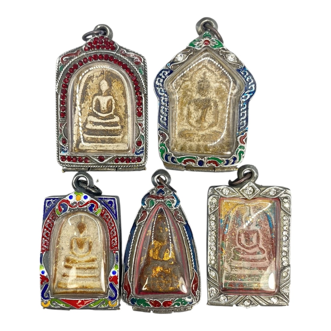 A Lot of 5 Vintage Thai Buddhist Amulets with Enamel and Jewel Accents, 16WT: A curated lot of five vintage Thai Buddhist amulets, each encased in ornate metal frames with enamel detailing and jewel accents. The amulets depict traditional seated Buddha iconography, with varying