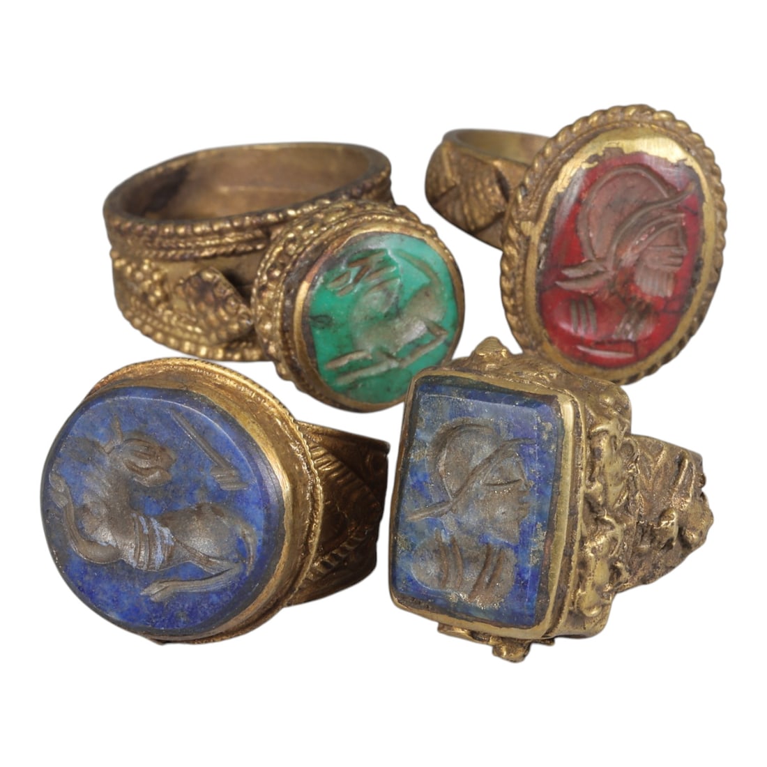 Lot of 4 Antique Qajar Period Gilt Intaglio Signet Rings, 64WP: A collection of four antique signet rings from the Qajar period, each set in ornate gilt metal with characteristic decorative detailing. The rings feature varied gemstone intaglios: one with turquoise