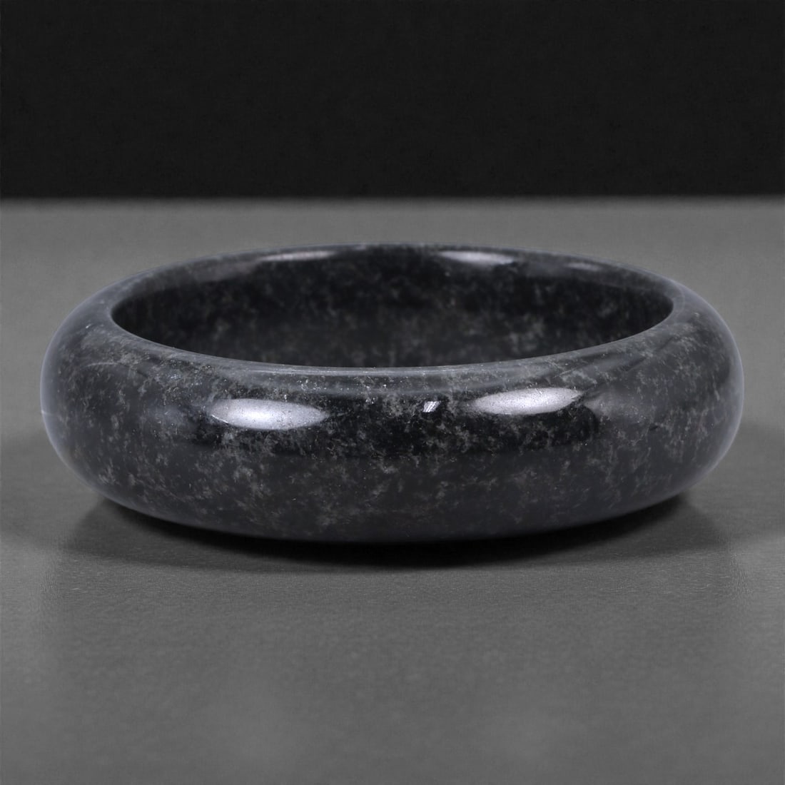 A Chinese Jadeite Bracelet Bangle, 6.4cm Inner Diameter, 13WE: Carved from jadeite, the bracelet is formed as a continuous circular bangle with a rounded cross-section and a uniformly polished surface. The interior and exterior edges are smoothly finished, indica
