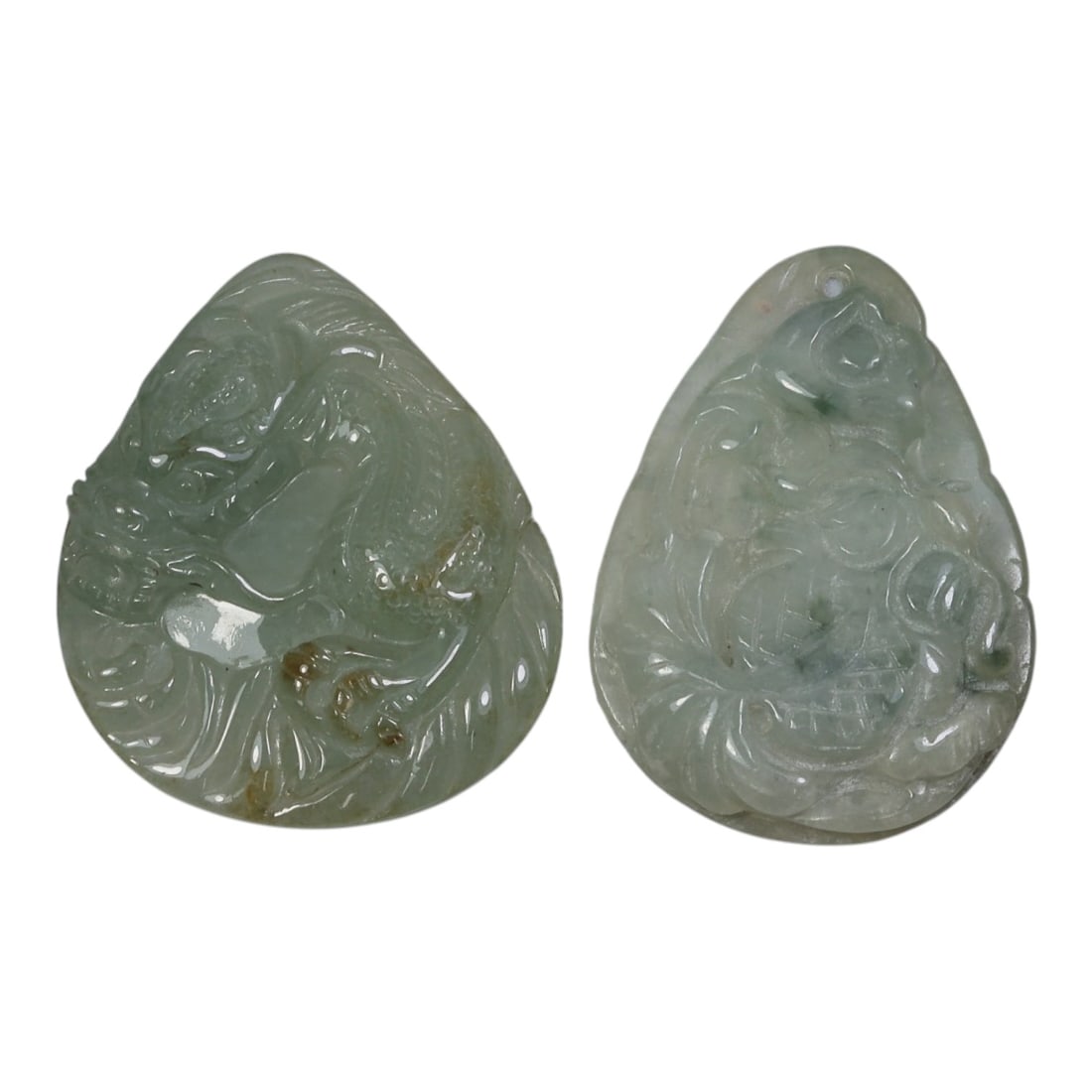 Lot of 2 Antique Oriental Chinese Jadeite Jade Pendants, 24AG: The lot comprises two teardrop-shaped jadeite pendants, each carved from pale green stone with natural tonal variations and inclusions. The left pendant features a high-relief carving of a mythical be