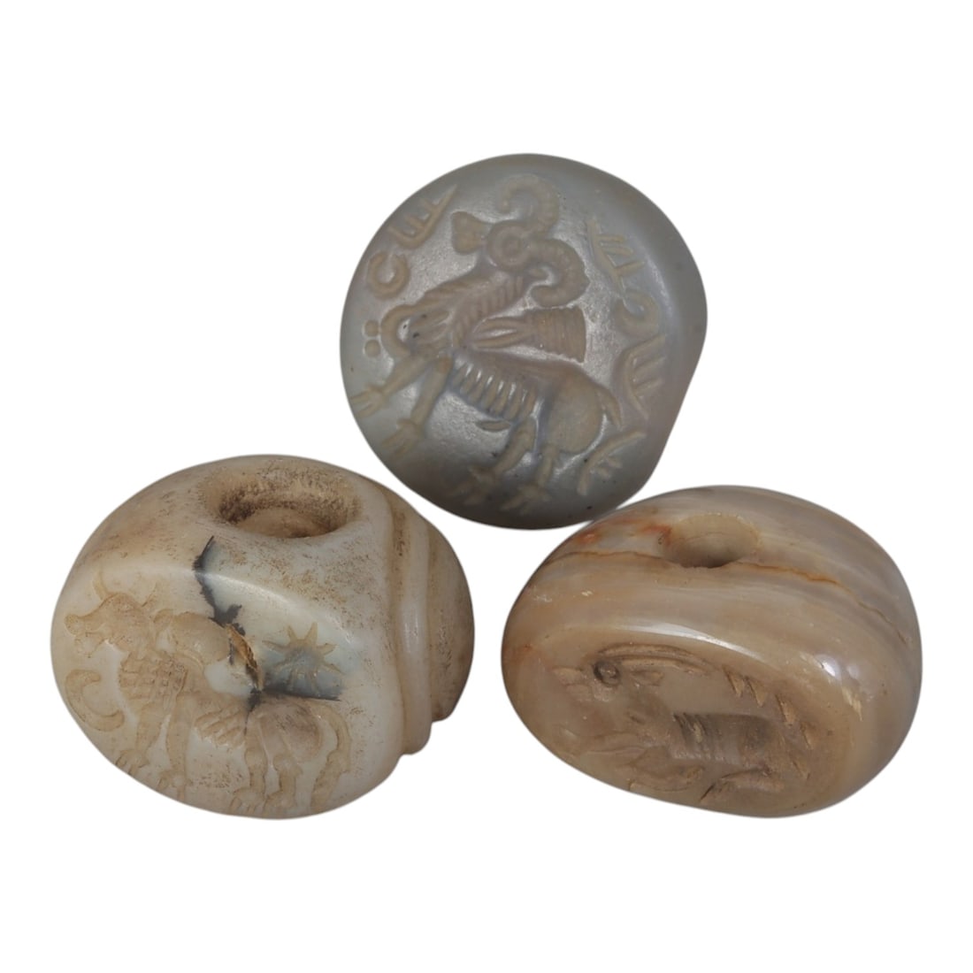 Lot of 3 Ancient Sasanian Stone Stamp Seals, Circa 3rd-7th Century CE, 65WP: A collection of three Sasanian period stamp seals, carved from agate and banded stone, each featuring a central drilled hole for suspension. The seals display characteristic Sasanian iconography: incl