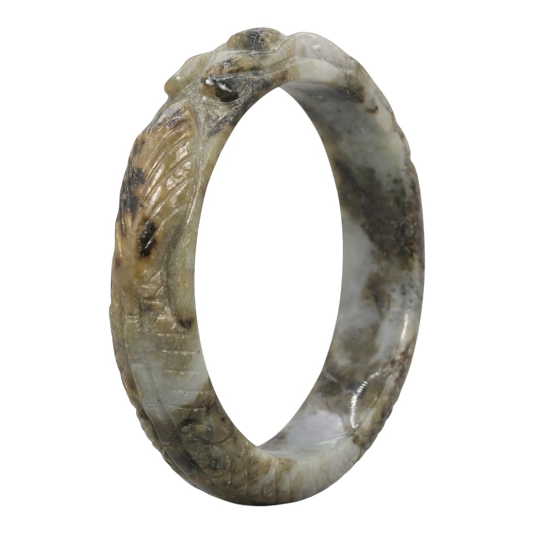 A Chinese Carved Jadeite Jade Bangle Bracelet, 20th Century, 70ZL: A fine jadeite bangle of circular form, masterfully carved in relief with a continuous band of a sinuous dragon coiling around its circumference. The stone exhibits a striking variegated palette, with