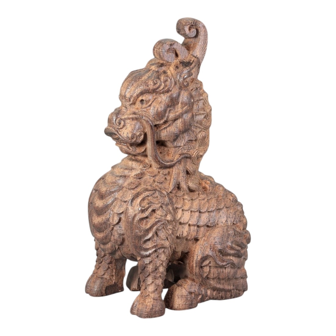 A Chinese Agarwood Qilin Figurine, 20th Century, 50FC: Carved from agarwood with natural tonal variation and a rich brown patina, the figurine depicts a seated qilin (mythical auspicious beast) in the round. The head features a curled, spiraling crest, la