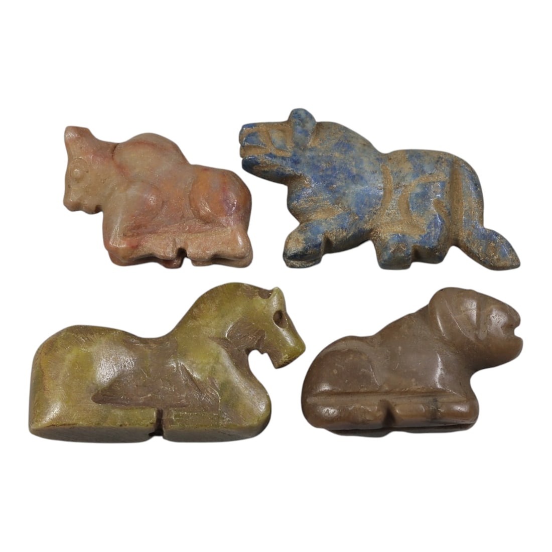 Lot of 4 Ancient Bactrian Zoomorphic Stone Amulets, Circa 3rd-1st Millennium BCE, 58AE: The group comprises four carved zoomorphic amulets depicting recumbent quadrupeds, including stylized bulls, felines, and horses, characteristic of ancient Bactrian art. The pieces are worked in varie