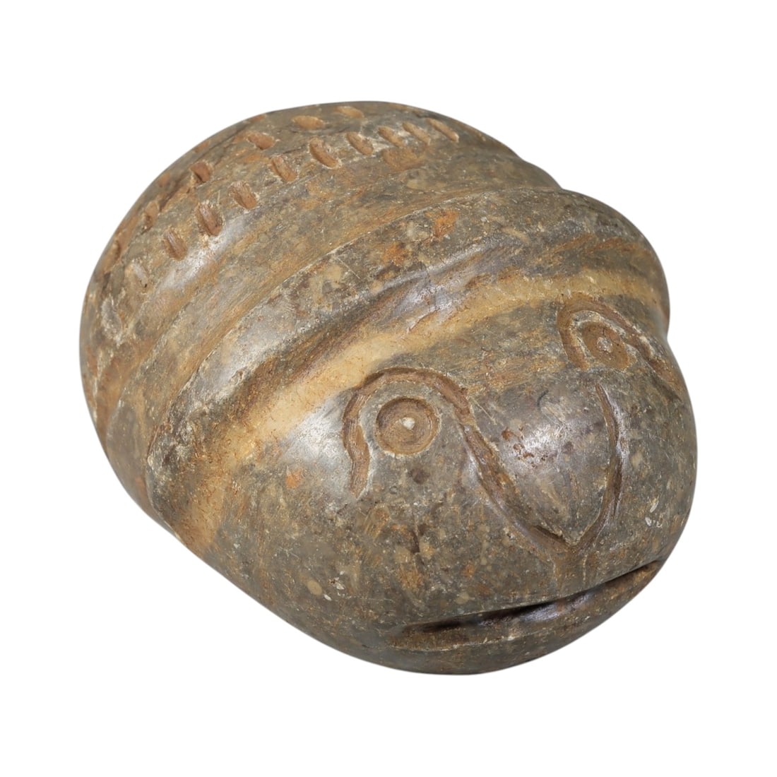 Ancient Silk Road Stone Weight, 47BA: A carved stone weight from the Silk Road region, of rounded form with incised decoration. The front features a stylized animal face, possibly representing a bird or owl, with defined eyes, beak, and m