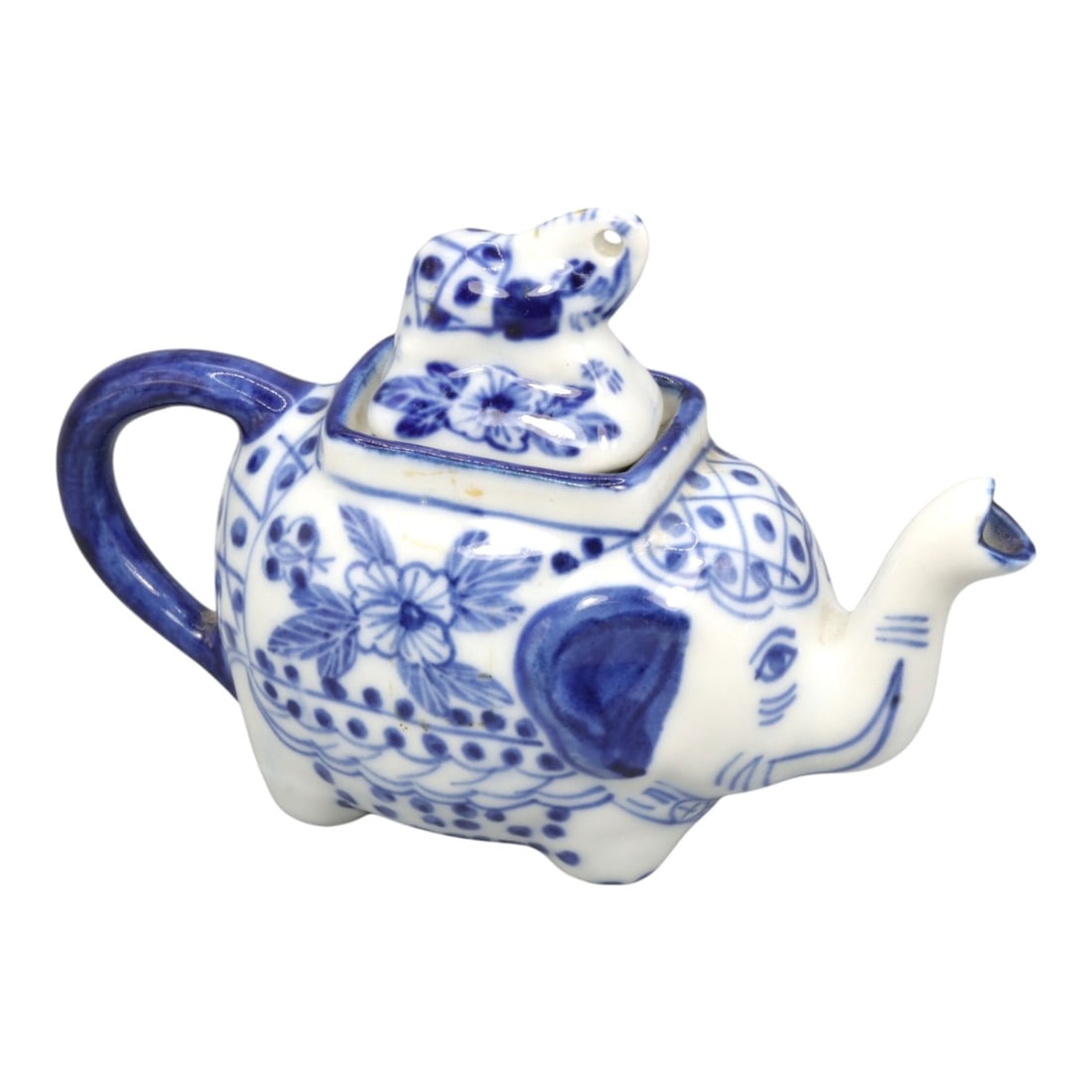 A Chinese Porcelain Elephant-Form Teapot, 20th Century, 46FK: Modeled in the form of a recumbent elephant, the teapot is constructed from white porcelain and decorated in underglaze cobalt blue. The elephant's raised trunk functions as the spout, while a looped 