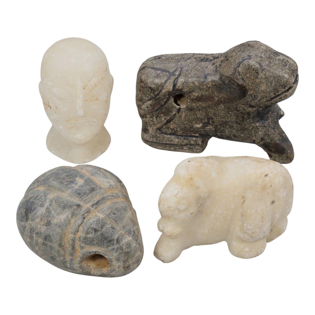 Lot of 4 Ancient Near Eastern Stone Amulets Figurines, 77WP: A collection of four ancient stone relics, carved from varied materials including light-colored alabaster and dark grey stone. The set includes: a stylized human head carving, a quadruped animal figur