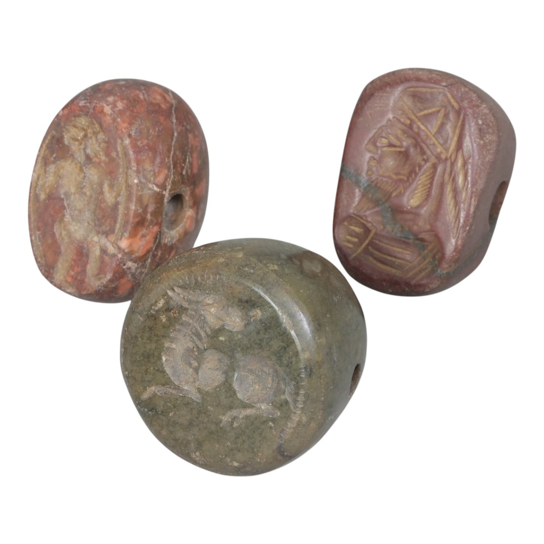 Lot of 3 Sasanian Stone Stamp Seals, Circa 3rd-7th Century CE, 99AE: Comprising three seals carved from stone, including reddish and greenish examples with natural veining and color variation. Each seal is rounded to ovoid in form, with a central perforation for suspen
