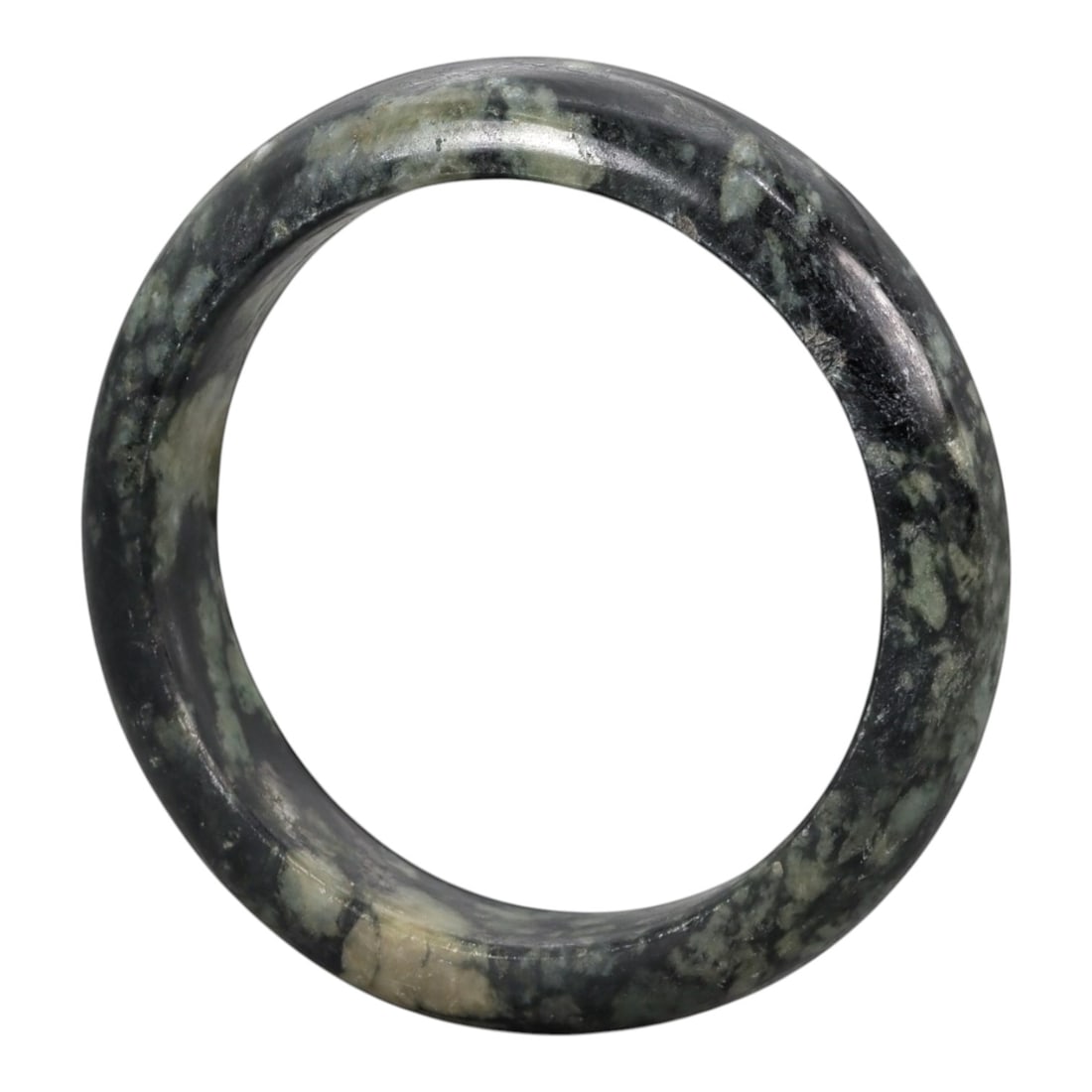A Chinese Jadeite Jade Bangle Bracelet, 20th Century, 95ZK: Carved from jadeite jade with a deep blackish-green base and irregular pale green and creamy-white mottling throughout, the bangle is formed as a solid circular band with a flattened rounded cross-sec