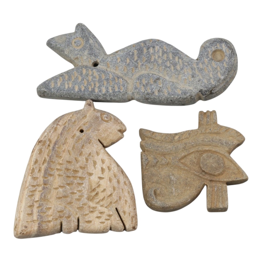Lot of 3 Ancient Near Eastern & Egyptian Stone Amulets, 23WT: Three carved stone amulets, including two Near Eastern animal figures and one Egyptian Eye of Horus motif, worked from grey and beige stone with incised details and surface patina. The first is a recl