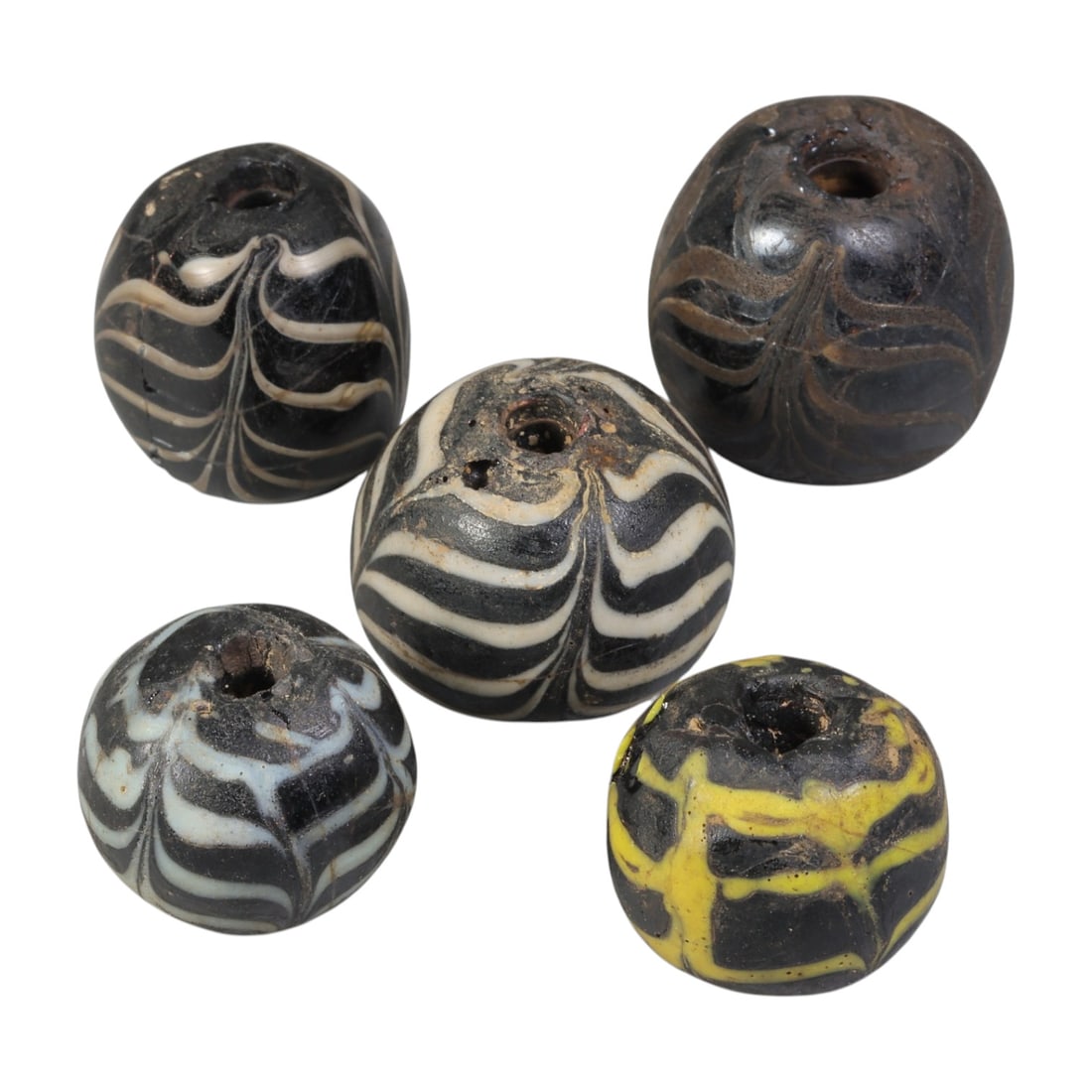 Lot of 5 Antique Islamic Feather-Patterned Glass Beads, Circa 9th-14th Century, 39WM: A group of five spherical glass beads, each with a central perforation. The beads feature characteristic feather-patterned decoration, created by trailing contrasting coloured glass over a dark base. 