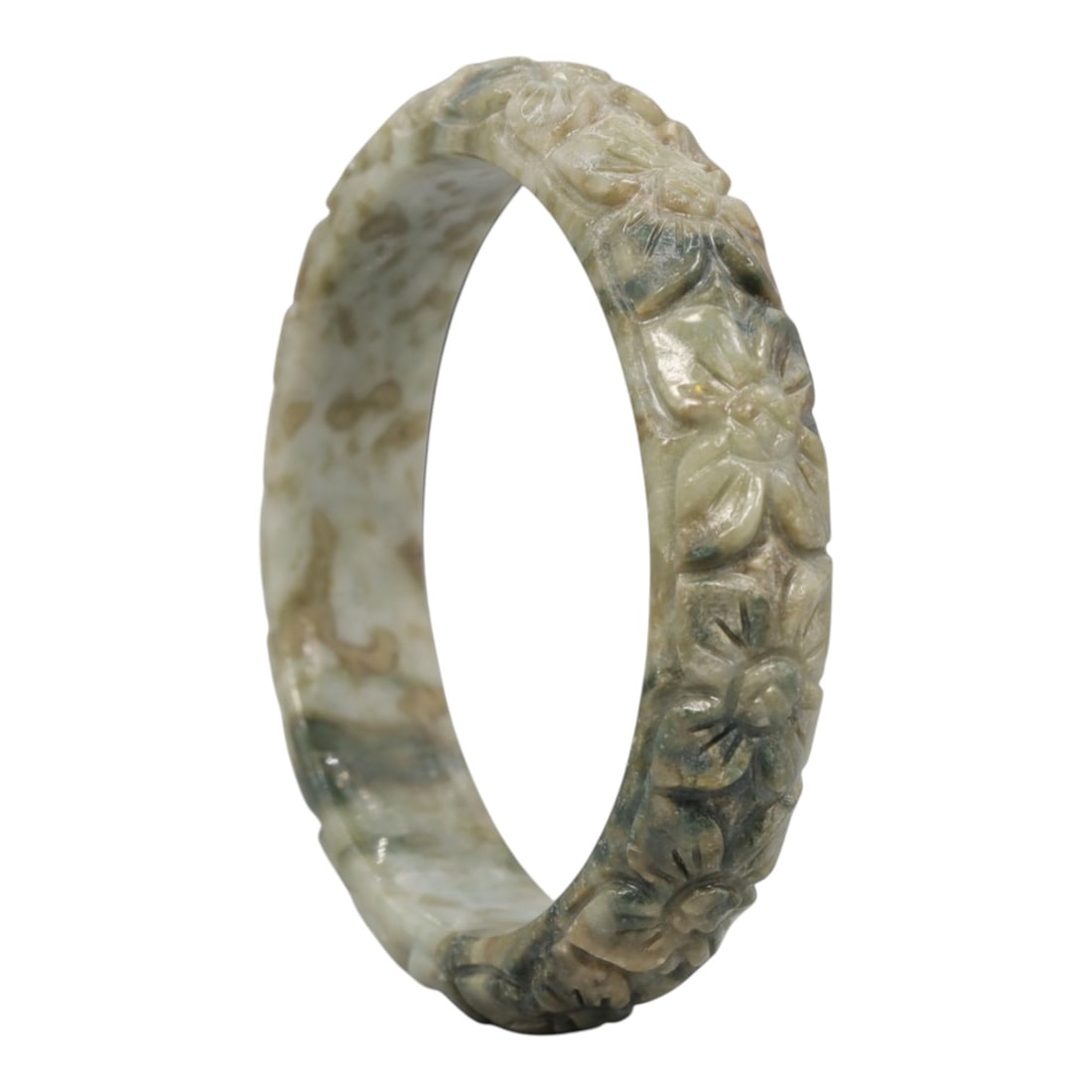 A Chinese Carved Jadeite Jade Bangle Bracelet, 20th Century, 79ZL: A fine jadeite bangle of flattened circular form, masterfully carved in relief with a continuous band of chrysanthemum blossoms. The stone exhibits a striking variegated palette, with a pale milky-gre