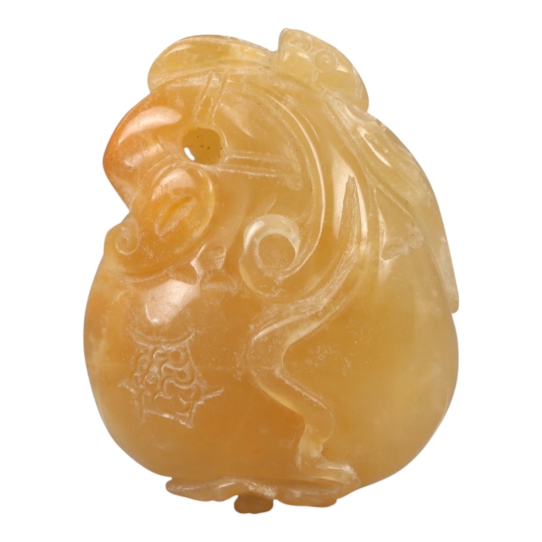 A Chinese Amber-Colored Hardstone Pendant with Zoomorphic Mask, 20th Century, 80FC: Carved from an amber-colored translucent hardstone or composite material, the pendant is worked in relief as a stylized zoomorphic mask, likely drawing on lion or mythical beast imagery. The form is c