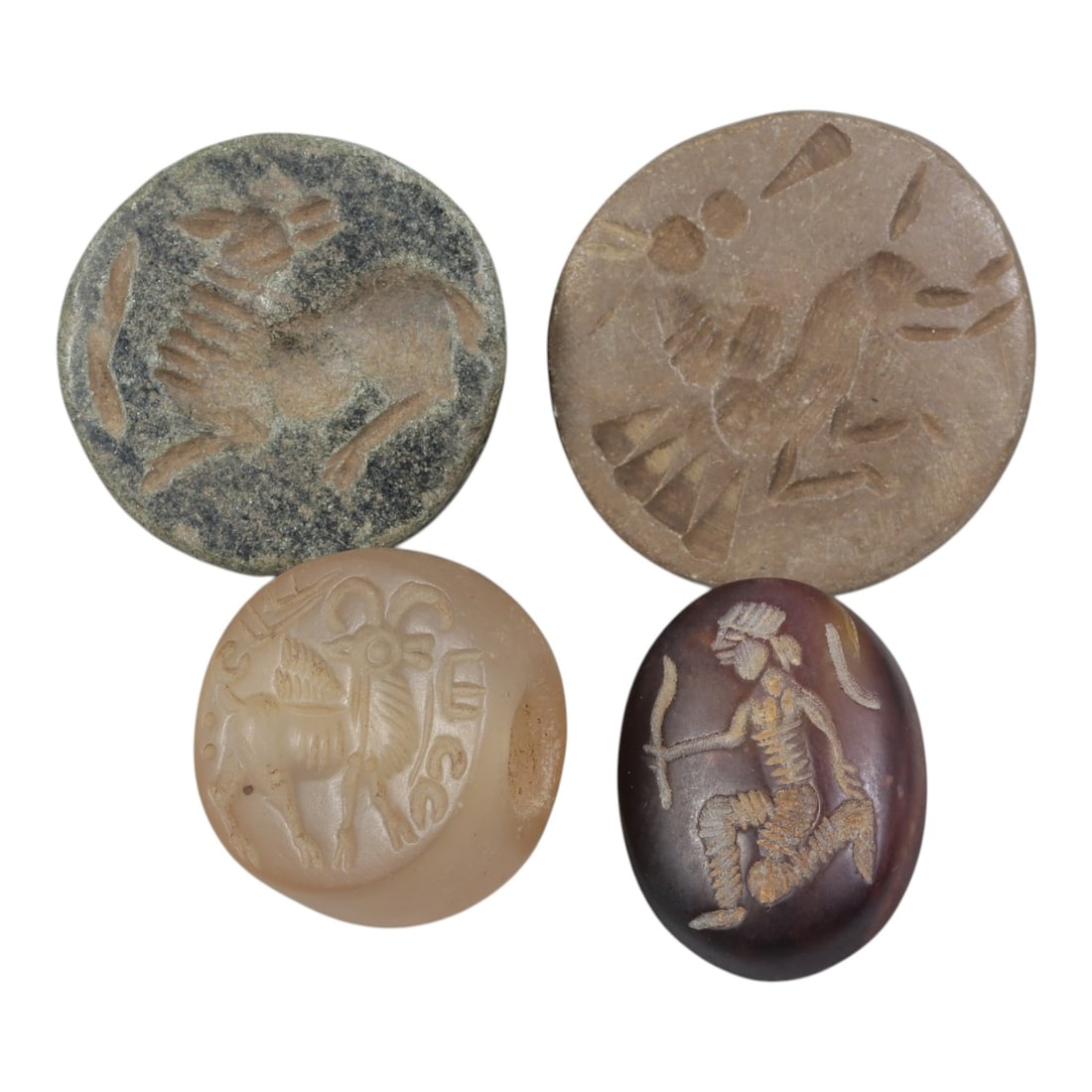 Lot of 4 Ancient Near Eastern Intaglio Stamp Seals, Circa Iron Age, 36AE: The group comprises four stamp seals of varying materials and forms, characteristic of Near Eastern glyptic traditions. The two disc-shaped seals are carved from stone, each depicting a quadruped anim