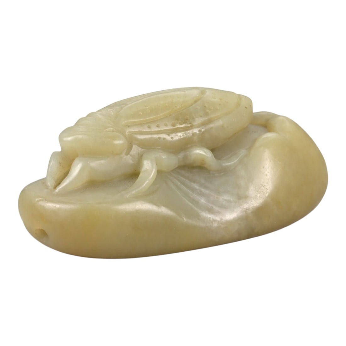 A Chinese Jade Cicada Carving, 20th Century, 5FB: Carved from pale yellow jade with a creamy, semi-translucent appearance and scattered natural inclusions, the object represents a cicada carved in relief against an oval ground. The insect is shown fr