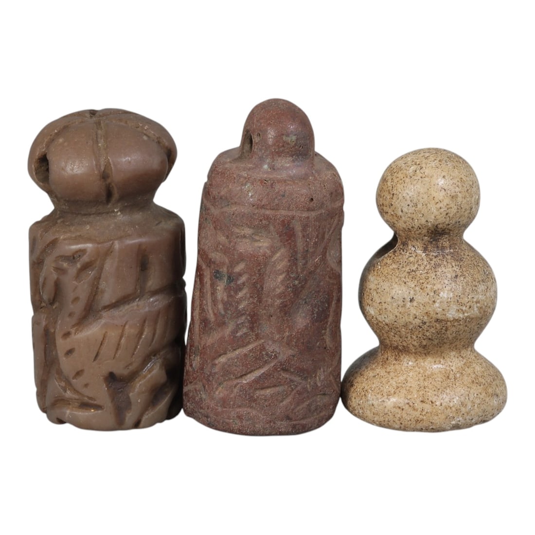 Lot of 3 Ancient Mesopotamian Cylinder Seal and Stamps, 79WM: A collection of three ancient Mesopotamian stone seals and stamps, carved from brown and light-toned stone. The set includes: a reddish-brown cylinder seal engraved with zoomorphic motifs, a carved br